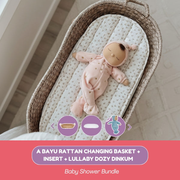 Baby changing basket with a pink doll on a textured surface, with a pink banner at the bottom.