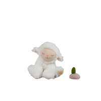 White plush lamb toy with a small green and pink object on a white background
