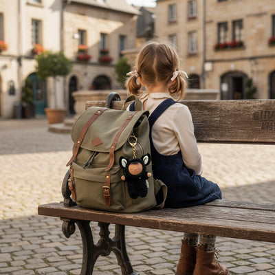 Child with a backpack sitting on a bench in an old town square