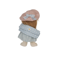 Doll wearing a pink hat with a bow and a blue checkered dress on a white background