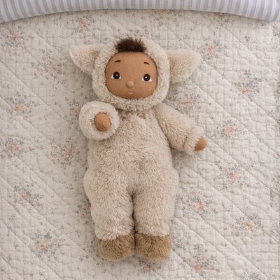 Stuffed animal toy in a fluffy outfit on a floral quilted surface