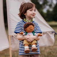Child holding a doll with a teepee in the background