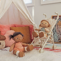 Two dolls in a child's room with a teepee and colorful pillows.