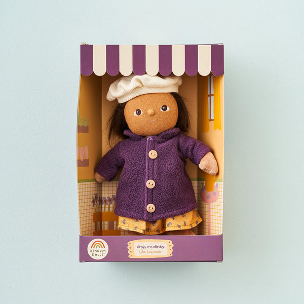 Toy doll in a purple coat and white hat in a decorative box on a light blue background