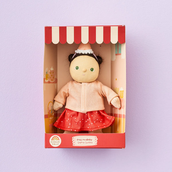 Doll in a box with a red and white striped roof on a light purple background