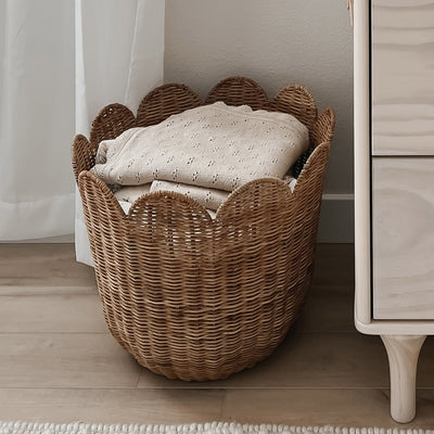 Functional brown rattan storage basket. Featuring scalloped edges, this basket is the perfect size for storing toys, laundry, towels and more. Use as décor storage in nurseries, bedrooms or anywhere in your home. 