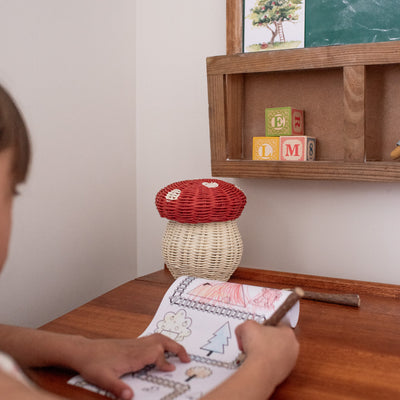 red and white rattan kids mushroom basket with coloured pencils for indoor play.