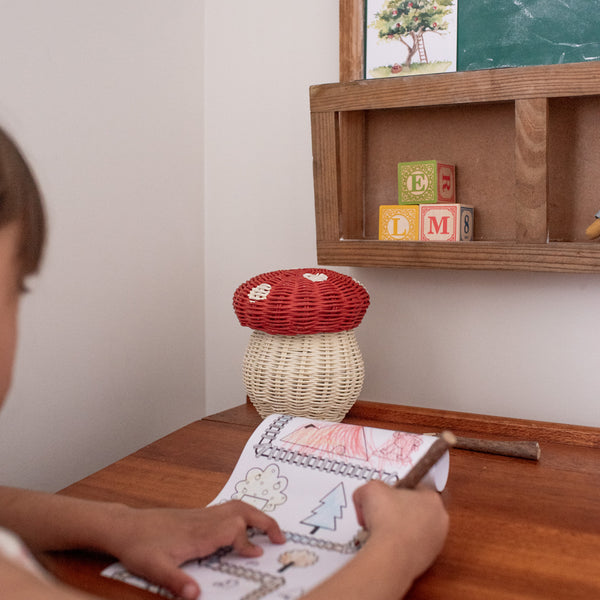 red and white rattan kids mushroom basket with coloured pencils for indoor play.