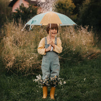 Olli Ella See Ya Umbrella Blue Butter colour way with child pictured in rain with flowers in his gumboots