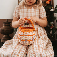 Olli Ella Halloween Berry Basket with orange stripe child putting treat in basket